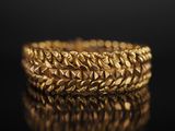 gros plan d'un bracelet en or sur une surface noire