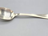 silver spoon sitting on a gray surface with a small spoon sticking out of it ' s side