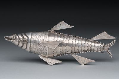 silver fish figurine on grey background with black background