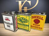 three vintage shell oil cans sitting on top of a wooden table