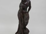 une statue antique en bronze représentant une femme tenant un panier