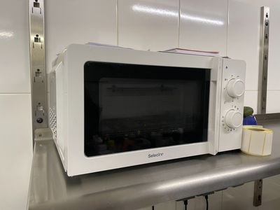 un micro-ondes blanc posé sur un plan de travail dans une cuisine