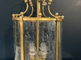 a brass and glass lantern with two candles inside on a marble table