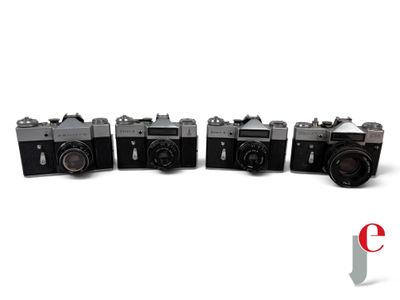 four old cameras are lined up in a row on a white surface