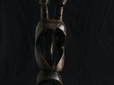 une sculpture en bois représentant un homme à deux cornes sur fond noir