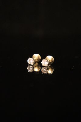 a pair of diamond stud earrings on a black surface