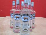quatre bouteilles de vodka posées sur une table devant un mur rouge
