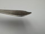 someone is holding a spoon with a silver handle on a white surface
