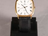 a close up of a watch on a stand on a white surface