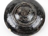 a black bowl on a white surface with a white background
