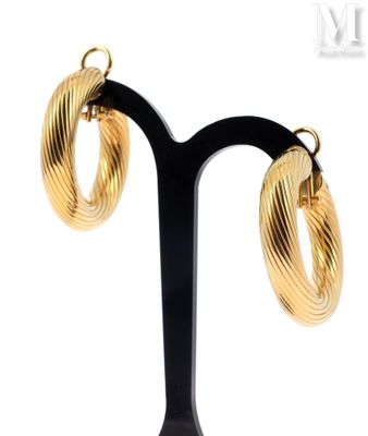 pair of gold toned hoop earrings on a black stand