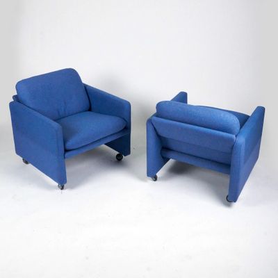 pair of blue chairs with casteors and foot rests against a white wall