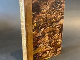 an old book with a brown cover sitting on top of a table