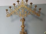 a gold colored metal cross with candles on it