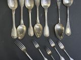 six cuillères en argent et six cuillères en argent posées sur un fond noir