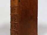 an old book with a brown leather cover sitting on a white surface