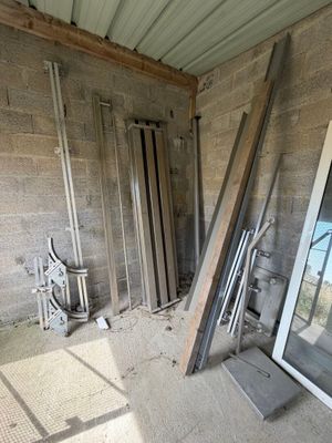 Plusieurs morceaux de bois sont empilés dans une pièce dont la porte est fermée.