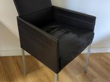 une chaise noire posée sur un parquet en bois dur