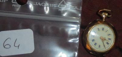 une petite montre de poche en or posée à côté d'un sac en plastique