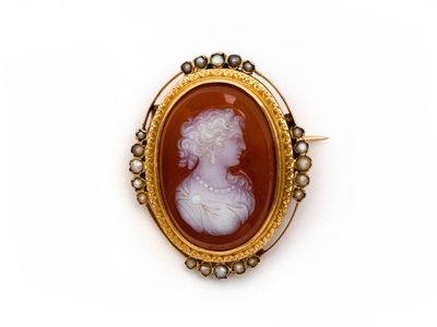 une broche antique en camée représentant une dame parée de perles, dans un cadre en or