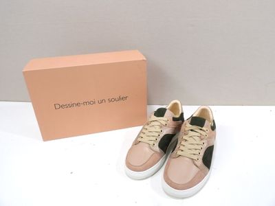 Les chaussures sont posées sur la table, à côté d'une boîte rose.