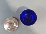 a blue glass and a silver cup sitting on a table