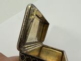 a person holding a small silver box on a white surface