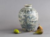 un vase bleu et blanc, avec deux poires à côté