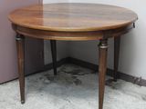 une table ronde avec un plateau en bois, placée dans un coin