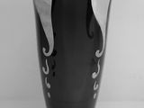 a black vase sitting on a table with a white wall in the background