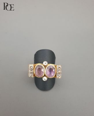 un gros plan d'une bague en or sertie de deux pierres roses