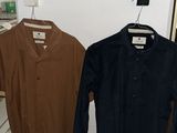 two shirts hanging on a clothes rack in a room