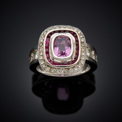 a close up of a pink sapphire and diamond ring on a black surface