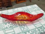 a red glass bowl sitting on a table with a blue and white tablecloth