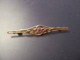 une image représentant une barrette dorée ornée de pierres rouges