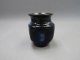 un petit vase bleu posé sur une surface blanche