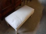 a white bench with a white cushion on it in a room