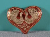 a red and gold heart shaped brooch with two birds on it
