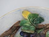 a plate with grapes and leaves on it on a table