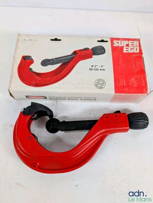 une photo d'un coupe-tube rouge posé sur une boîte