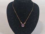 a necklace with a purple stone on a black mannequin