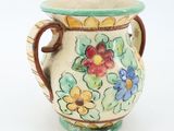 a small vase with flowers painted on it on a white surface