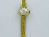 montre de couleur or jaune, avec un cadran blanc et un bracelet doré