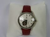 une montre blanche avec un bracelet rouge posée sur un coussin blanc