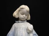 a figurine of a little girl holding a teddy bear