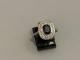 une photo d'une bague sertie d'un diamant et d'un saphir, posée sur un présentoir