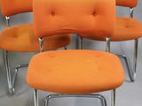 four orange chairs and a small ottoman in a room