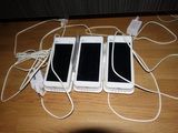 three white cell phones sitting next to each other on a wooden table