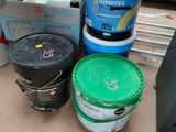 several buckets of paint sitting on the floor next to a tv
