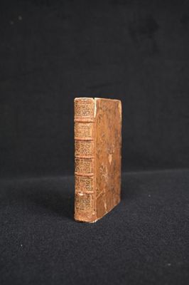an old book sitting on top of a black cloth covered table